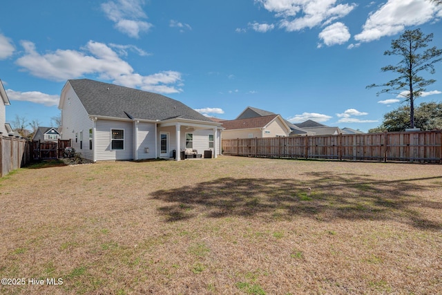 rear view of house featuring a yard and a fenced backyard