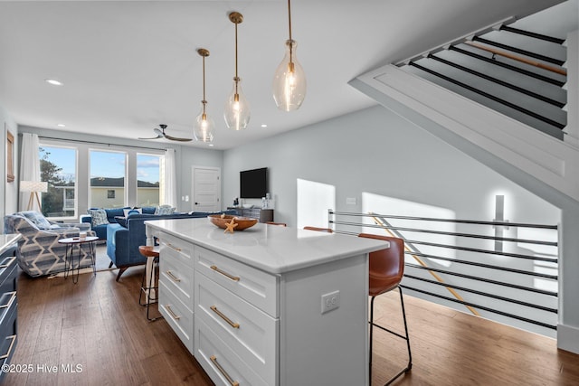 interior space featuring dark wood-style floors, white cabinetry, a kitchen breakfast bar, open floor plan, and a center island