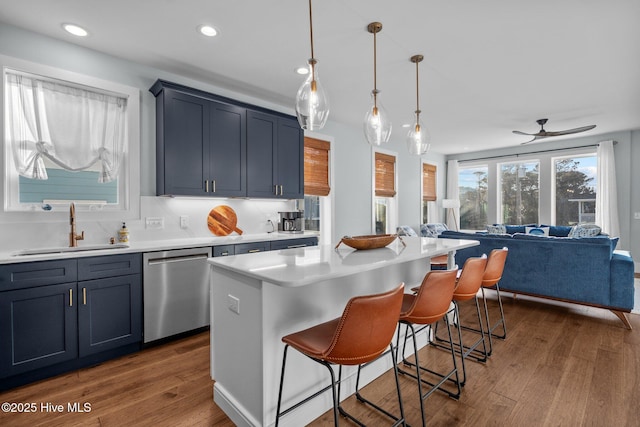 kitchen featuring dishwasher, wood finished floors, light countertops, and a sink