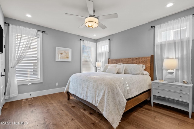 bedroom with visible vents, multiple windows, wood finished floors, and baseboards