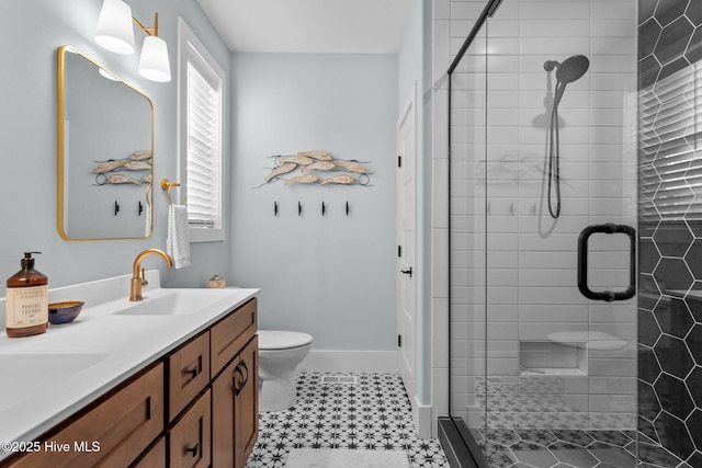 bathroom featuring toilet, a stall shower, a sink, double vanity, and baseboards