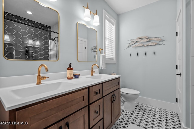 full bathroom with double vanity, toilet, baseboards, and a sink