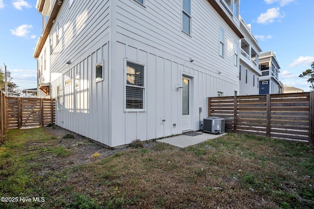 exterior space with a lawn, board and batten siding, central AC, and a fenced backyard