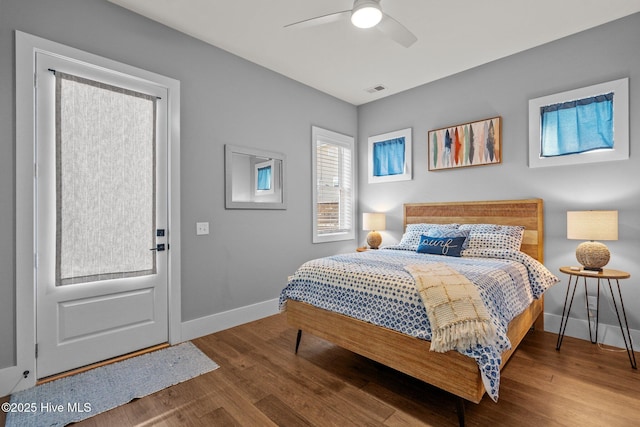 bedroom featuring ceiling fan, visible vents, baseboards, and wood finished floors