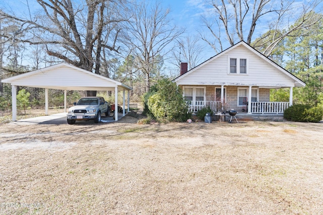 view of front of property featuring a porch, a chimney, a carport, and dirt driveway