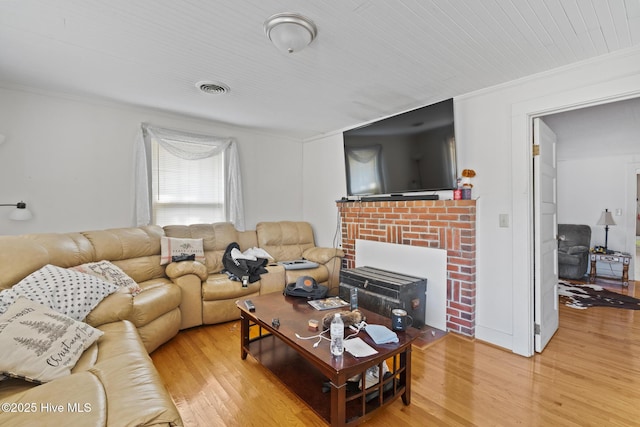 living area with light wood-style floors, visible vents, and ornamental molding