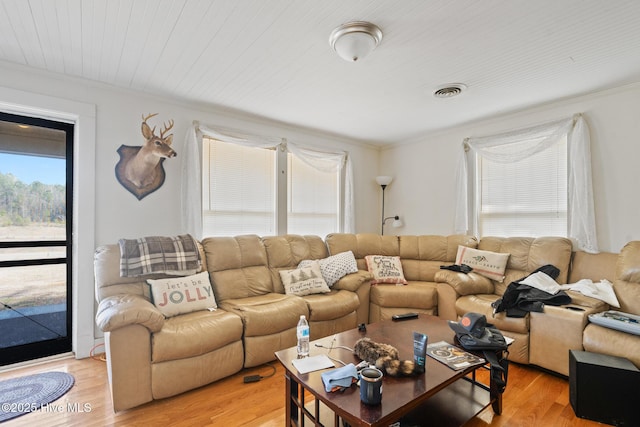 living area with ornamental molding, light wood finished floors, and visible vents