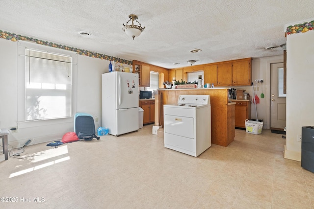 kitchen with brown cabinets, light floors, washer / clothes dryer, light countertops, and freestanding refrigerator