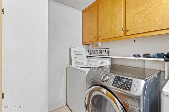 laundry area featuring cabinet space, a textured ceiling, baseboards, and separate washer and dryer