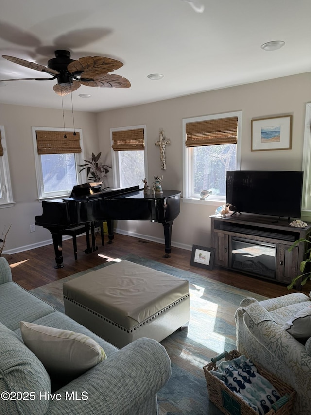 living room with ceiling fan, baseboards, and wood finished floors