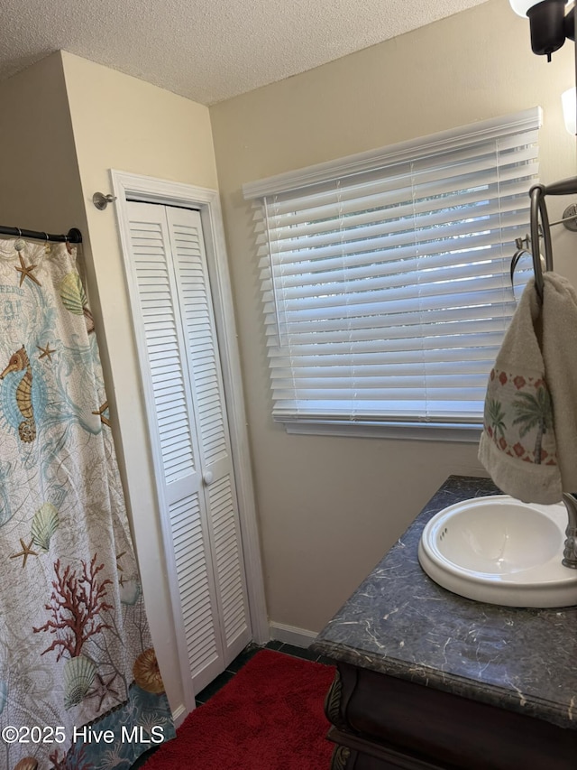 bathroom featuring a textured ceiling, curtained shower, vanity, a closet, and tile patterned floors