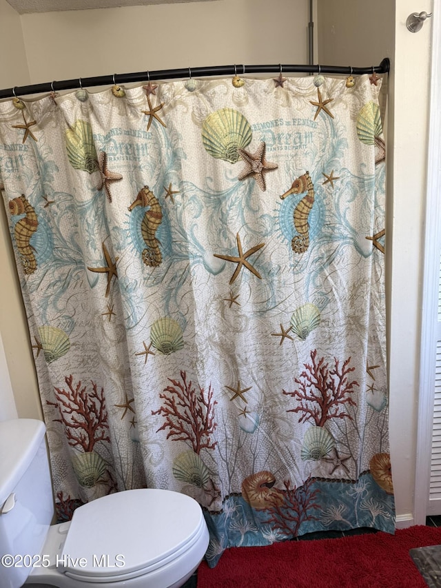 bathroom with a shower with shower curtain and toilet