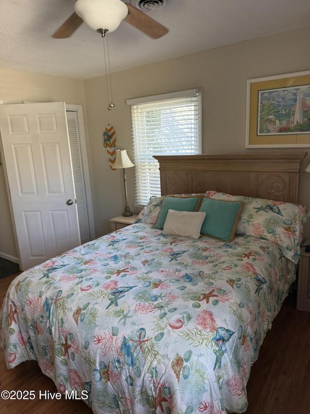 bedroom featuring a ceiling fan, visible vents, a closet, and wood finished floors