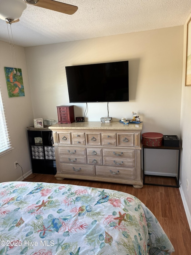 bedroom featuring dark wood-style floors, a textured ceiling, baseboards, and a ceiling fan