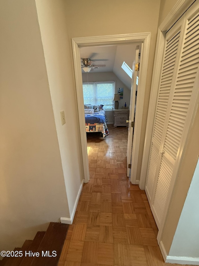 hall with vaulted ceiling and baseboards