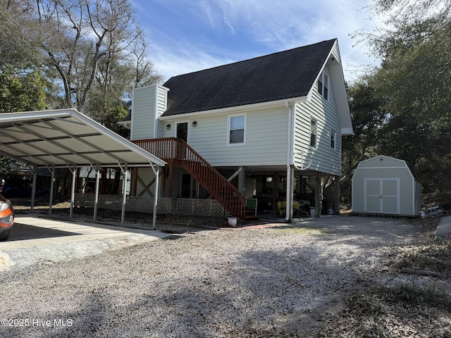 view of front facade featuring driveway, stairway, roof with shingles, an outdoor structure, and a shed