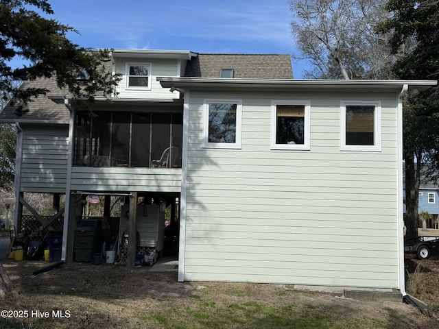 rear view of house featuring a shingled roof and a sunroom