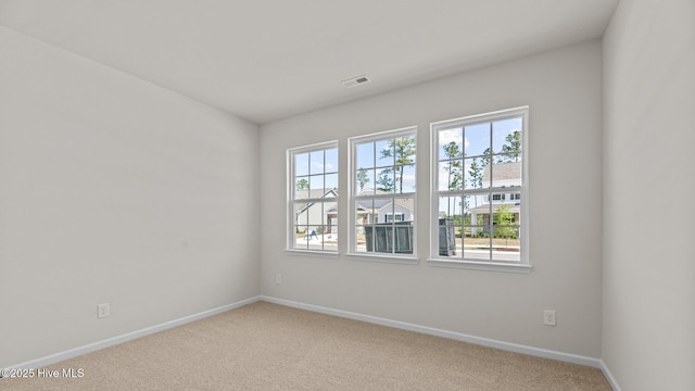 carpeted spare room featuring baseboards and visible vents