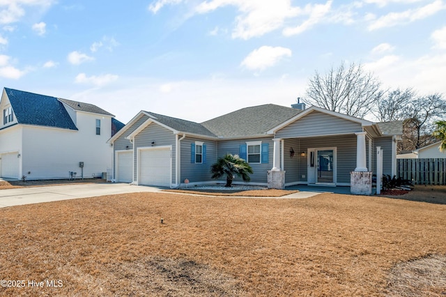 view of front of property with concrete driveway, roof with shingles, an attached garage, fence, and a front lawn