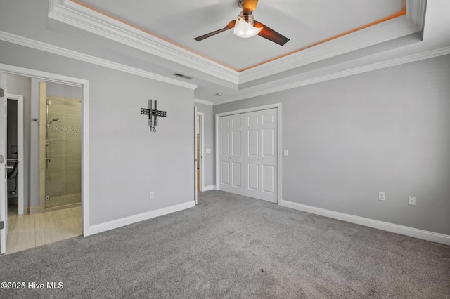 unfurnished bedroom with carpet, a raised ceiling, visible vents, and baseboards