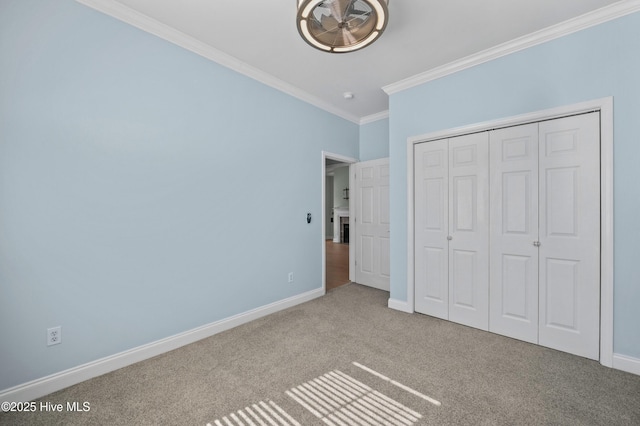 unfurnished bedroom with a closet, carpet flooring, crown molding, and baseboards