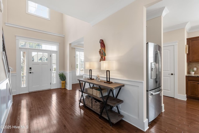 foyer entrance featuring a wainscoted wall, dark wood-style flooring, and crown molding