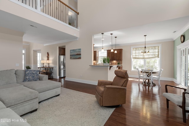 living area with dark wood-style floors, visible vents, ornamental molding, and baseboards