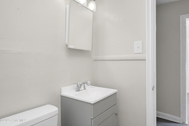 bathroom with tile walls, vanity, and toilet