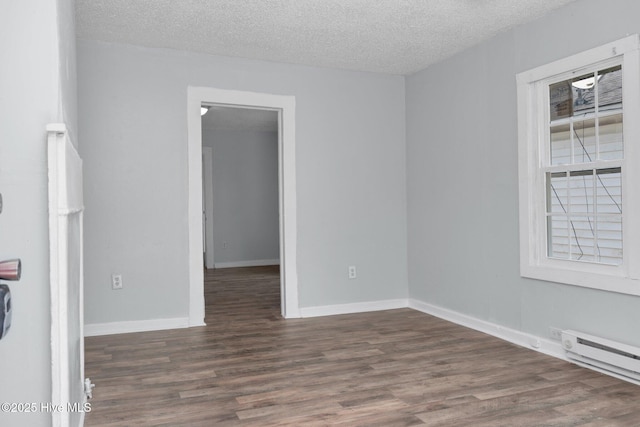 empty room with a textured ceiling, baseboards, baseboard heating, and wood finished floors