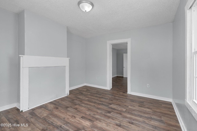 unfurnished room featuring baseboards, dark wood finished floors, and a textured ceiling