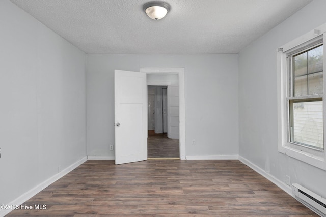 empty room with baseboards, a textured ceiling, baseboard heating, and wood finished floors