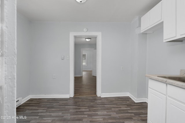 unfurnished dining area featuring dark wood-style floors, visible vents, and baseboards