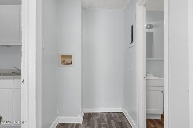 washroom featuring dark wood-style floors, a sink, hookup for a washing machine, and baseboards