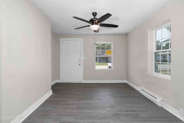 unfurnished room featuring baseboards, a textured ceiling, a baseboard heating unit, and dark wood-type flooring