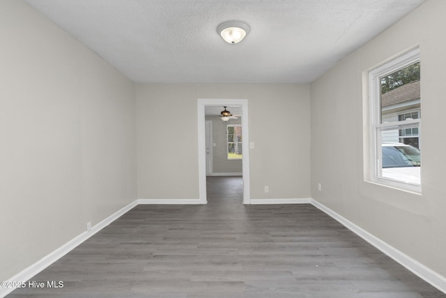 spare room with a textured ceiling, wood finished floors, and baseboards