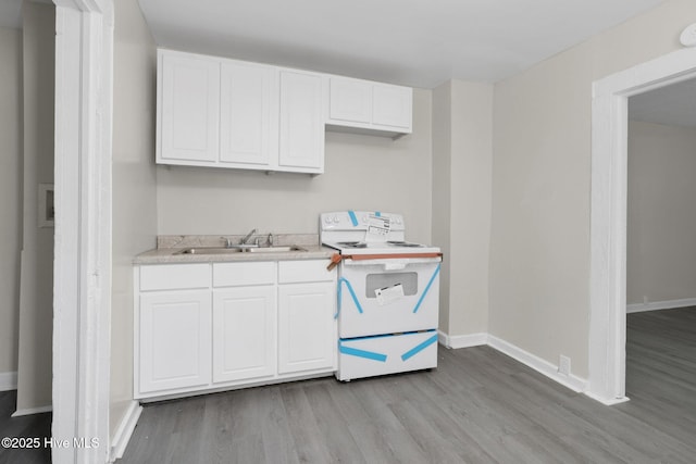 kitchen featuring white cabinets, electric range, light countertops, and a sink