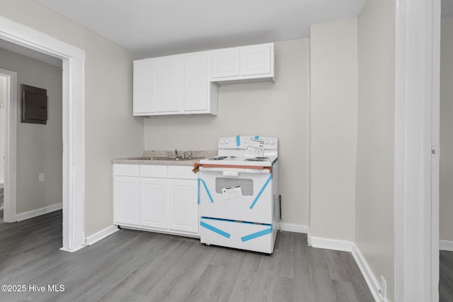 kitchen with light wood-type flooring, white cabinets, light countertops, and electric range