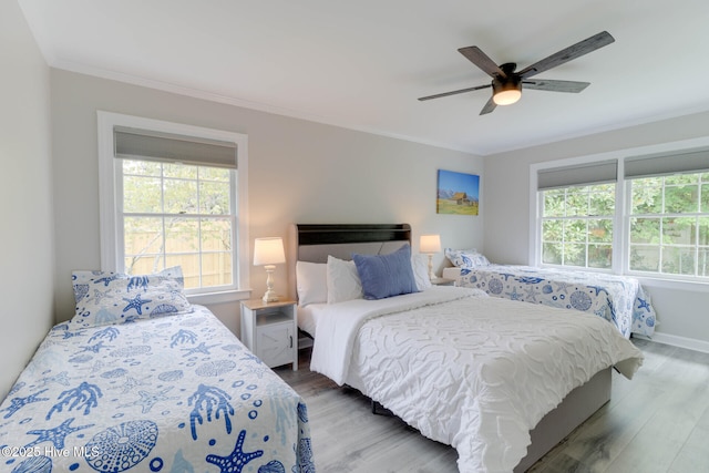 bedroom with crown molding, baseboards, ceiling fan, and wood finished floors