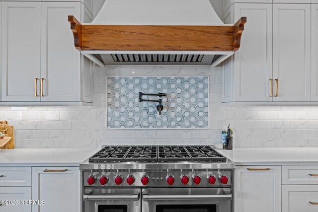 kitchen featuring custom range hood, light countertops, white cabinetry, and double oven range