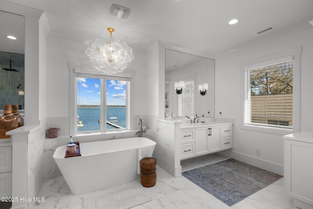 bathroom with marble finish floor, visible vents, a freestanding bath, and vanity