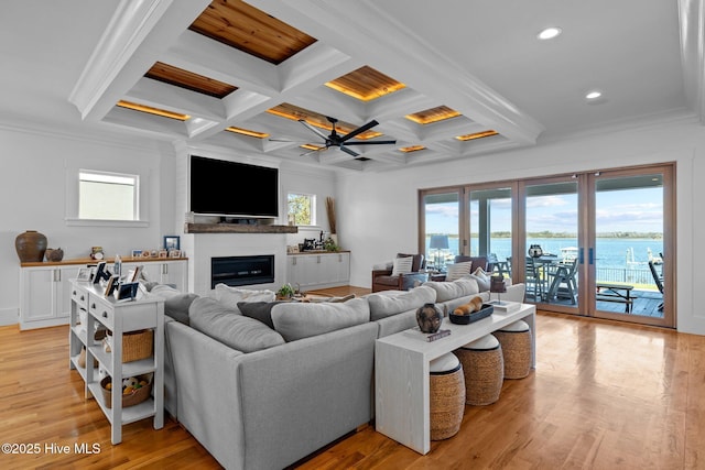 living area featuring light wood-style floors, coffered ceiling, a fireplace, and ornamental molding