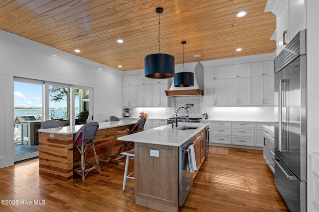 kitchen with wood ceiling, a kitchen island with sink, appliances with stainless steel finishes, and decorative backsplash