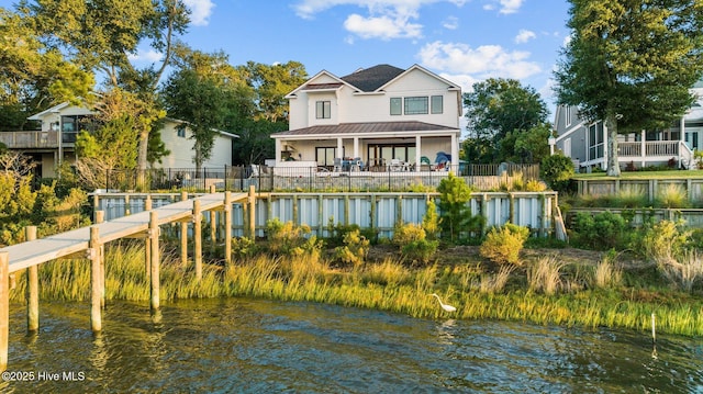 back of house with fence private yard, a standing seam roof, a water view, and metal roof