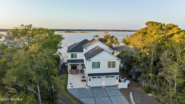 view of front of house featuring concrete driveway, a water view, a standing seam roof, metal roof, and a garage