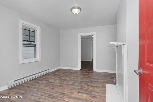 spare room featuring baseboard heating, wood finished floors, and baseboards