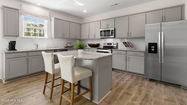 kitchen featuring stainless steel appliances, light wood finished floors, gray cabinets, and visible vents