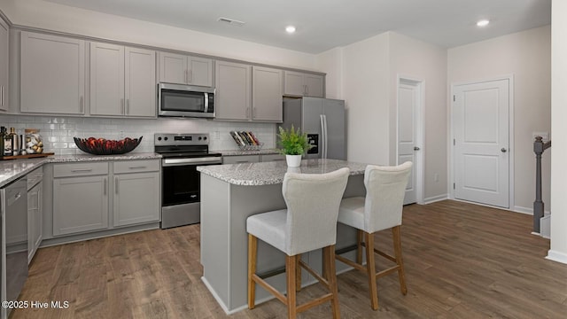 kitchen with visible vents, dark wood finished floors, gray cabinets, stainless steel appliances, and backsplash