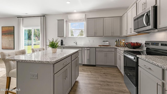 kitchen featuring appliances with stainless steel finishes, gray cabinets, and a kitchen breakfast bar