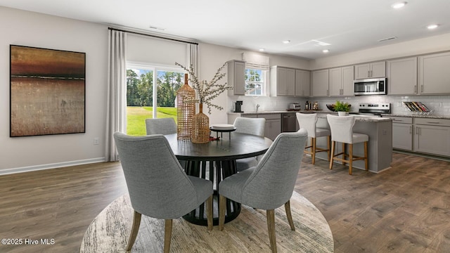 dining room with recessed lighting, dark wood-style flooring, and baseboards