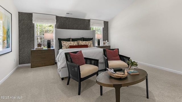 bedroom with lofted ceiling, light colored carpet, visible vents, and baseboards